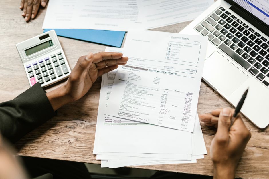 Persona revisando el extracto bancario con una calculadora para reclamar comisiones al banco