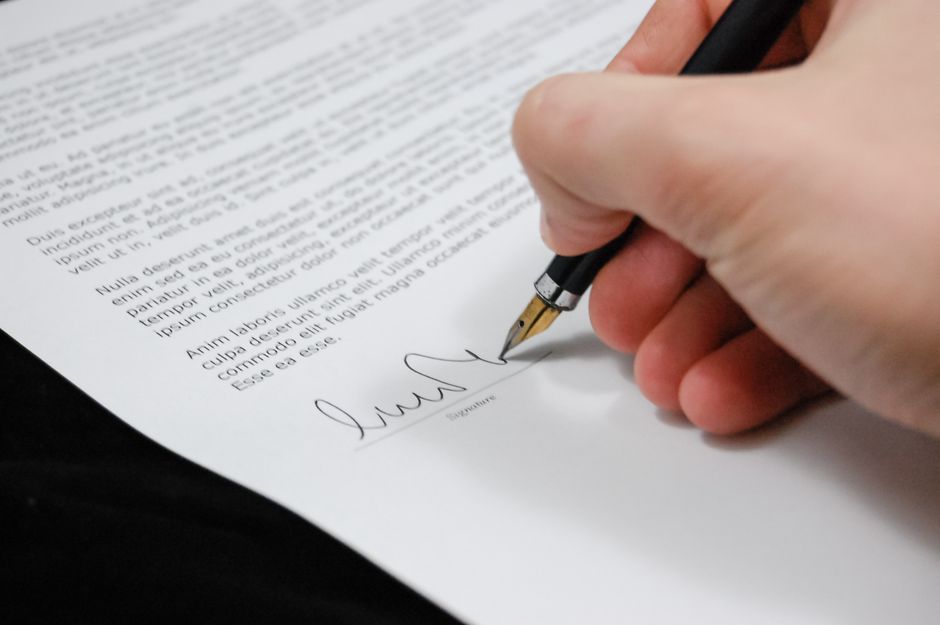 Firma de un escrito de reclamación de comisiones bancarias sobre la mesa