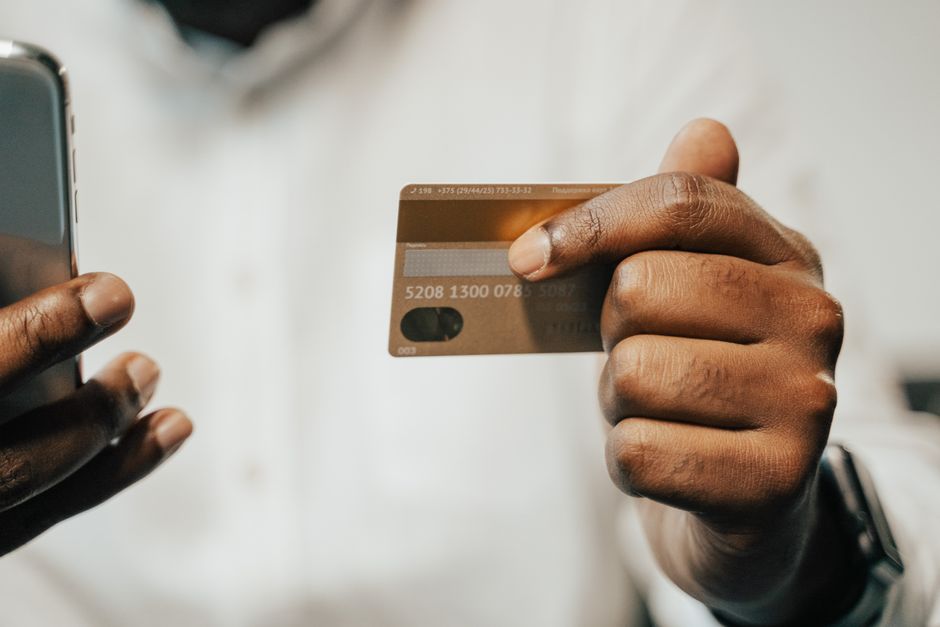 Persona haciendo una transferencia bancaria desde el móvil con una tarjeta en la mano