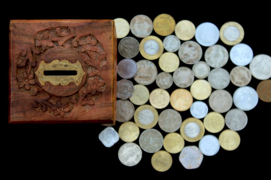 Caja de madera antigua junto a monedas, como metáfora de una cuenta bancaria olvidada con dinero dormido