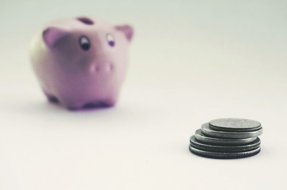 Hucha de cerdito rodeada de monedas, símbolo de la decisión entre cuenta remunerada y depósito a plazo fijo