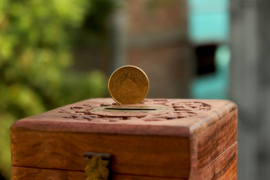 Hucha de madera con monedas doradas representando el ahorro en depósitos bancarios