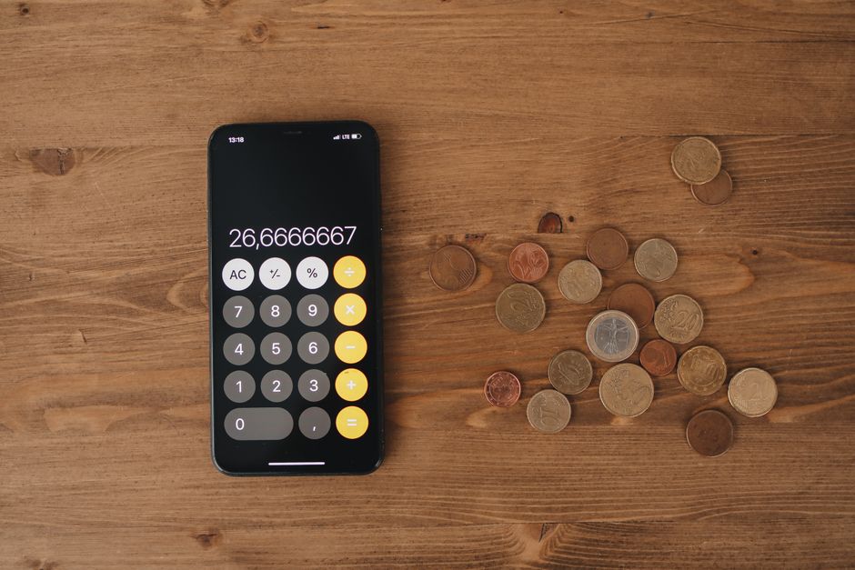 Calculadora y monedas sobre una mesa de madera representando cuentas bancarias