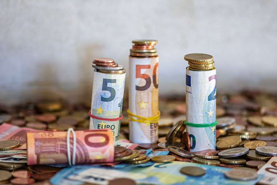 Billetes y monedas de euro enrollados y apilados sobre una mesa